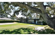 Front view of Del Mesa Carmel facility with a large tree and green lawn.