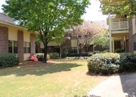 Exterior view of Mount Vernon Village courtyard with trees, shrubs, and brick buildings.