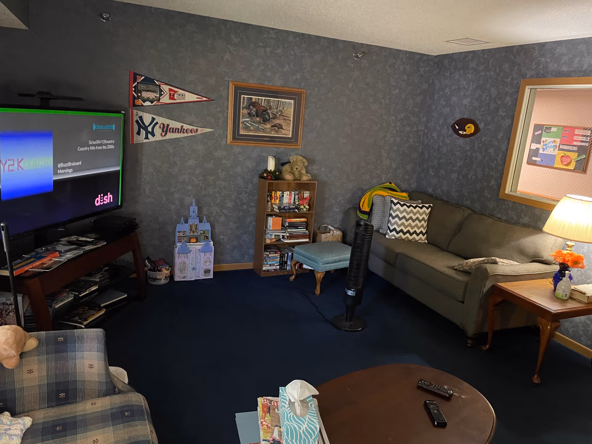 Cozy common living room with a sofa, armchair, TV, bookshelf, and coffee table.