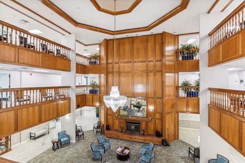 Spacious multi-level lobby with wood-paneled walls, a large chandelier, seating area, and balconies overlooking the atrium.