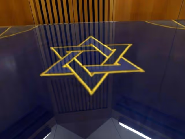 A reflective surface showing a yellow Star of David design, with wooden paneling and vertical slats in the background.