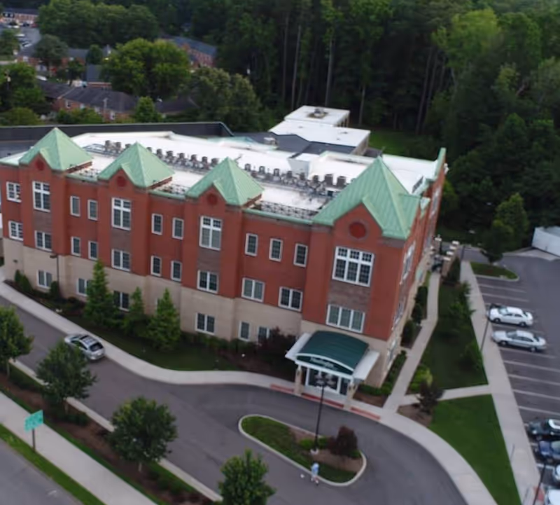 Aerial view of a brick-assisted living facility with green roofs and a front entrance canopy.