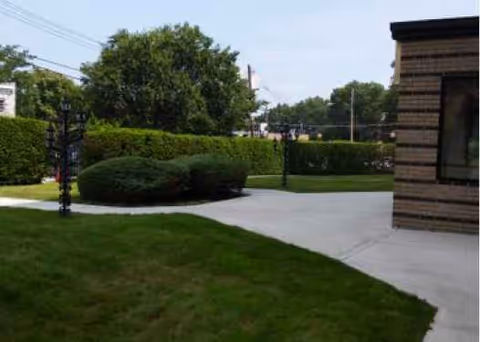 Exterior view of Laconia Nursing Home with manicured shrubs and a paved walkway.