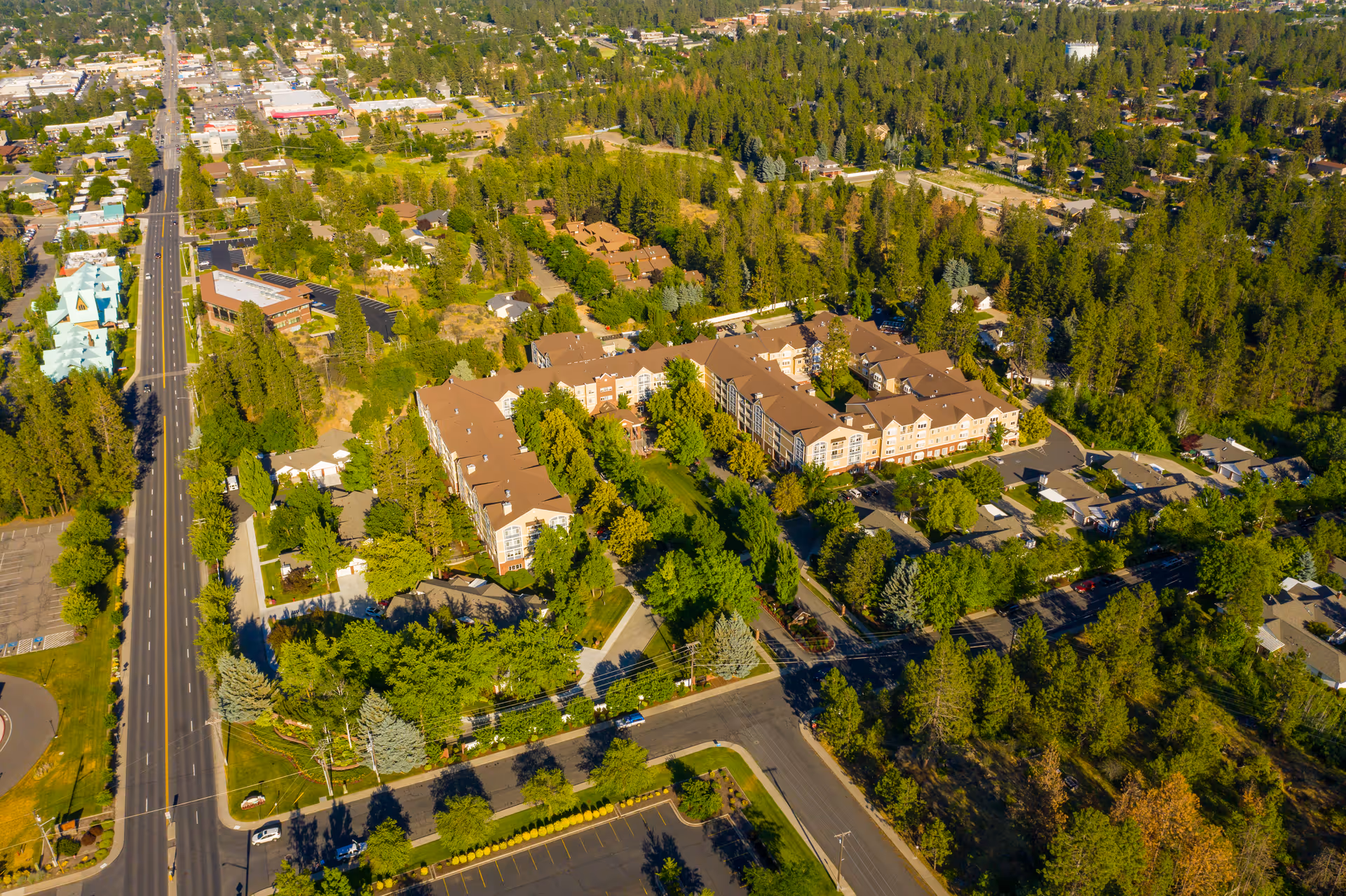 Aerial view of a senior living facility named Touchmark on South Hill surrounded by trees and greenery, with nearby roads and residential areas visible.