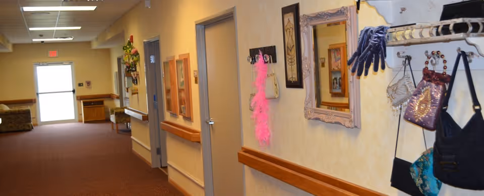 Interior hallway with handrails, doors, mirrors, seating at the end, and a wall rack holding purses and gloves.