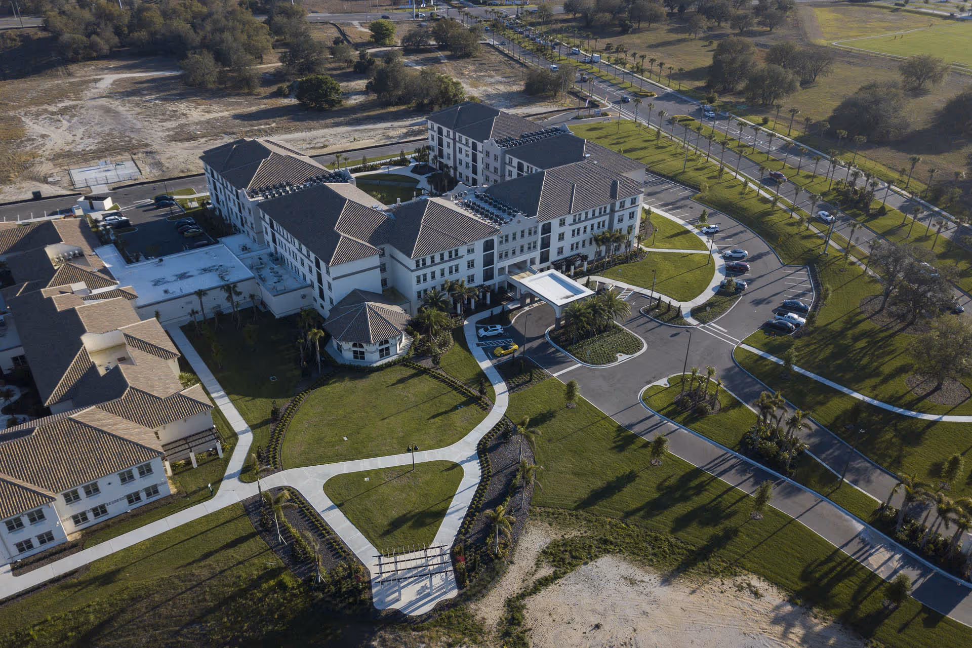 Aerial view of The Glades at ChampionsGate showing a multi-wing senior living building with a circular driveway, parking areas, and landscaped grounds.