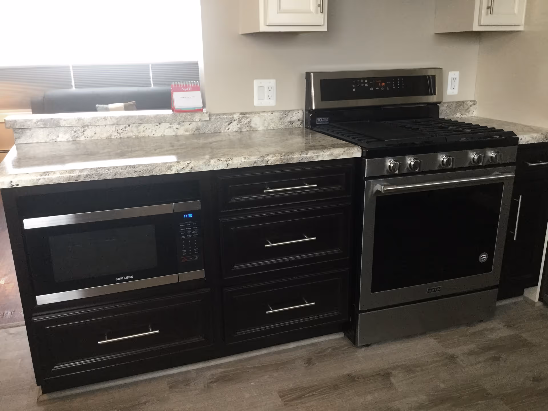Modern kitchen countertop with a built-in microwave, dark cabinets, and a stainless steel gas range.
