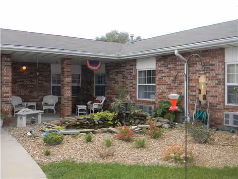 Brick senior living facility with a covered patio and rock garden seating.