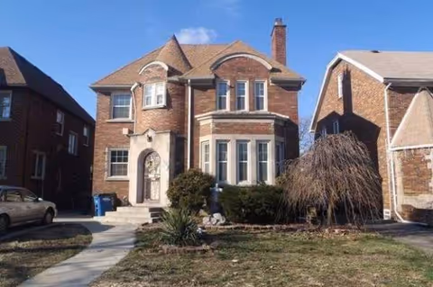 Brick two-story senior living facility with arched doorway and landscaped front yard.