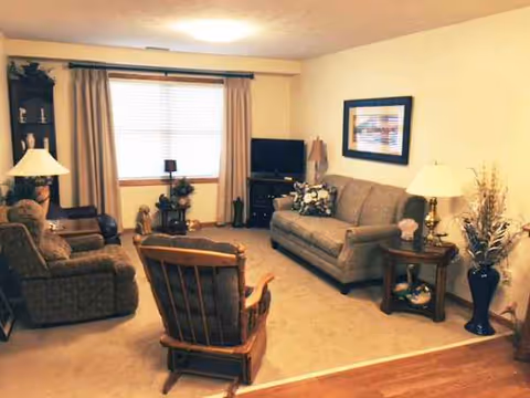 Cozy living room with sofa, chairs, lamps, TV, and decor in beige tones.