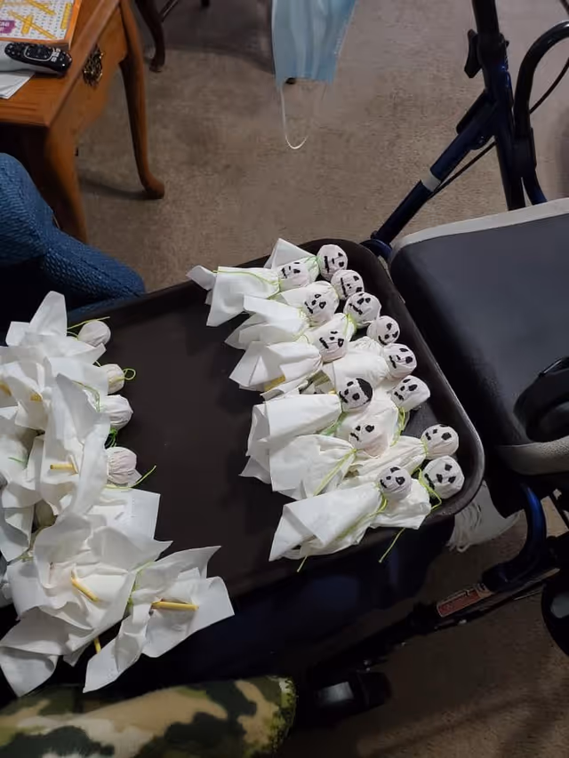 A tray filled with small tissue ghosts with drawn faces sits on a walker tray in a living room area.