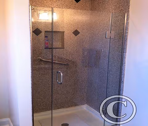 Glass-enclosed shower in a tiled bathroom with a grab bar and niche.
