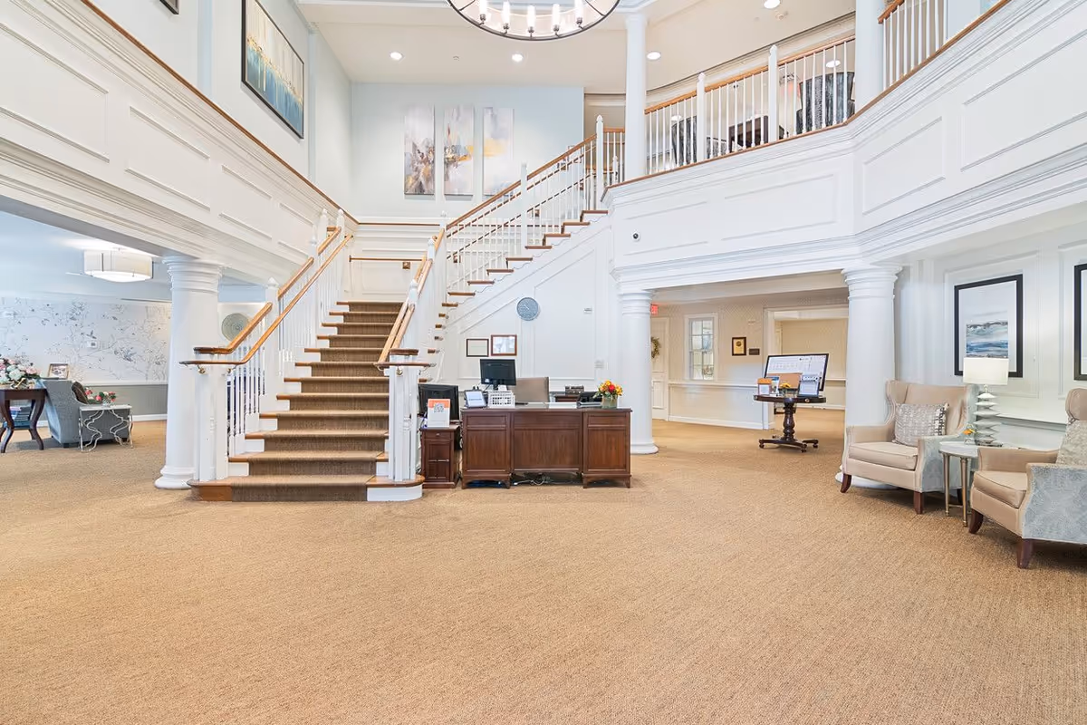 Spacious, well-lit lobby with a central carpeted staircase, reception desk, and seating areas.