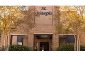 Brick facade of St. Joseph Nursing Home with trees and an entrance canopy.