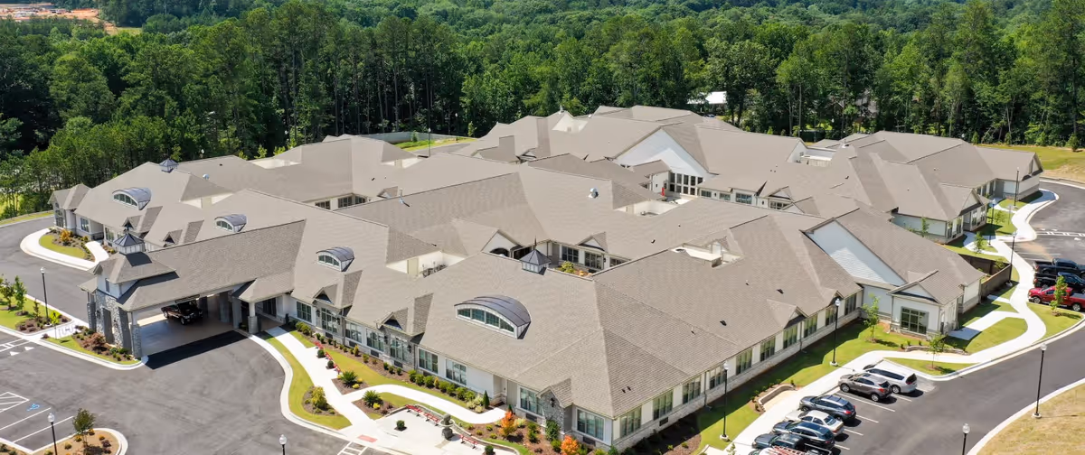 Aerial view of the Orchard at Athens senior living complex showing connected single-story buildings, parking areas, and surrounding trees.