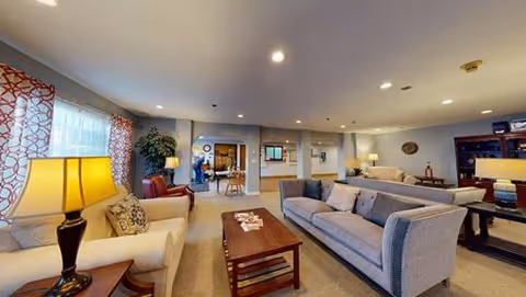 Spacious furnished common living room with sofas, armchairs, coffee tables, lamps, and a seating area.