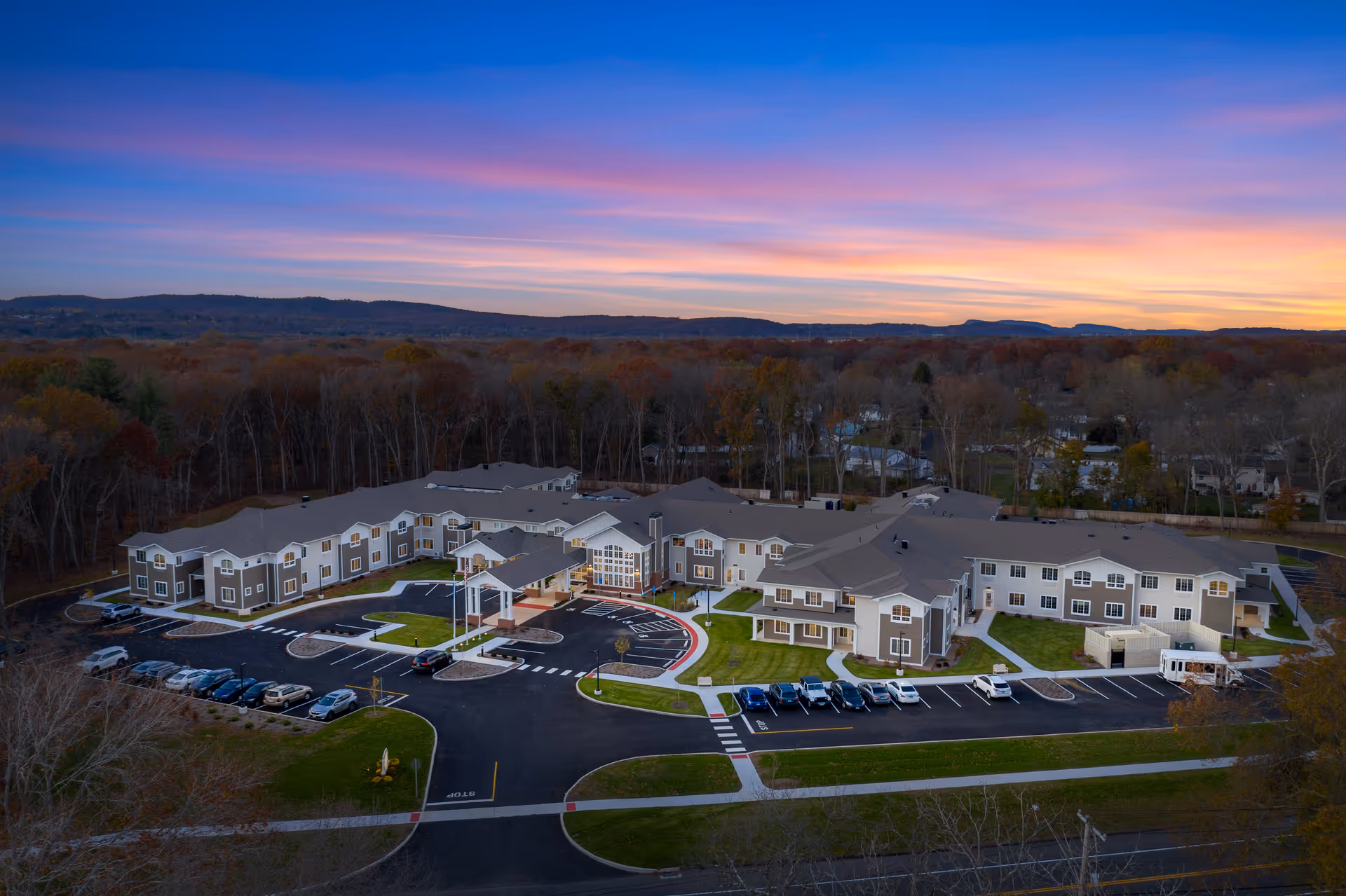 Aerial view of The Landing of North Haven senior living complex with parking lots and landscaped grounds at sunset.
