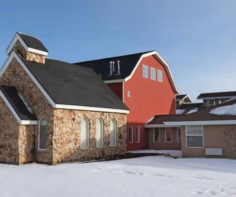 Exterior view of Elk Meadows Assisted Living and Memory Care building with stone and red siding.