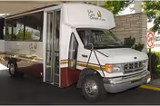 White and maroon Life Care Center of Boise shuttle bus parked under a covered entry with its passenger door open.