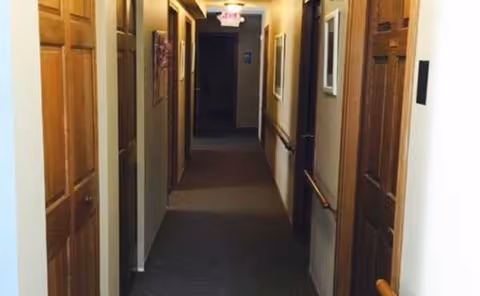 Long carpeted hallway with doors on both sides and an exit sign ahead.