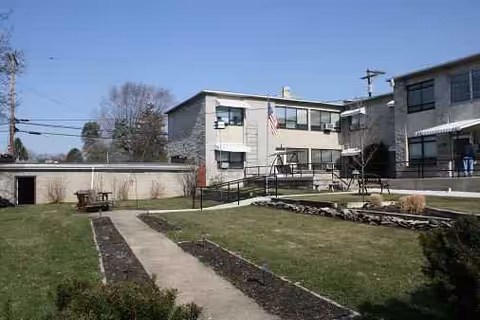 Exterior view of Hearthstone Retirement Home showing a walkway, lawn, and two-story building.