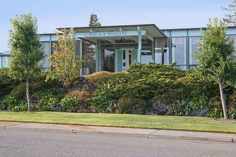 Front entrance of Crestwood Health and Rehab with green landscaping and large glass windows.