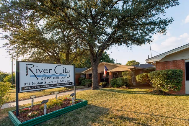 Front view of the River City Care Center sign and a single-story brick building with trees and a lawn.