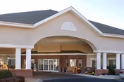 Front exterior view of the Life Care Center of Westminster building featuring a covered entrance with white columns, brick accents, and a peaked roof under a clear sky.