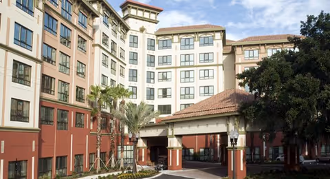 Front view of Freedom Pointe senior living building with beige and red exterior and arched entrance.