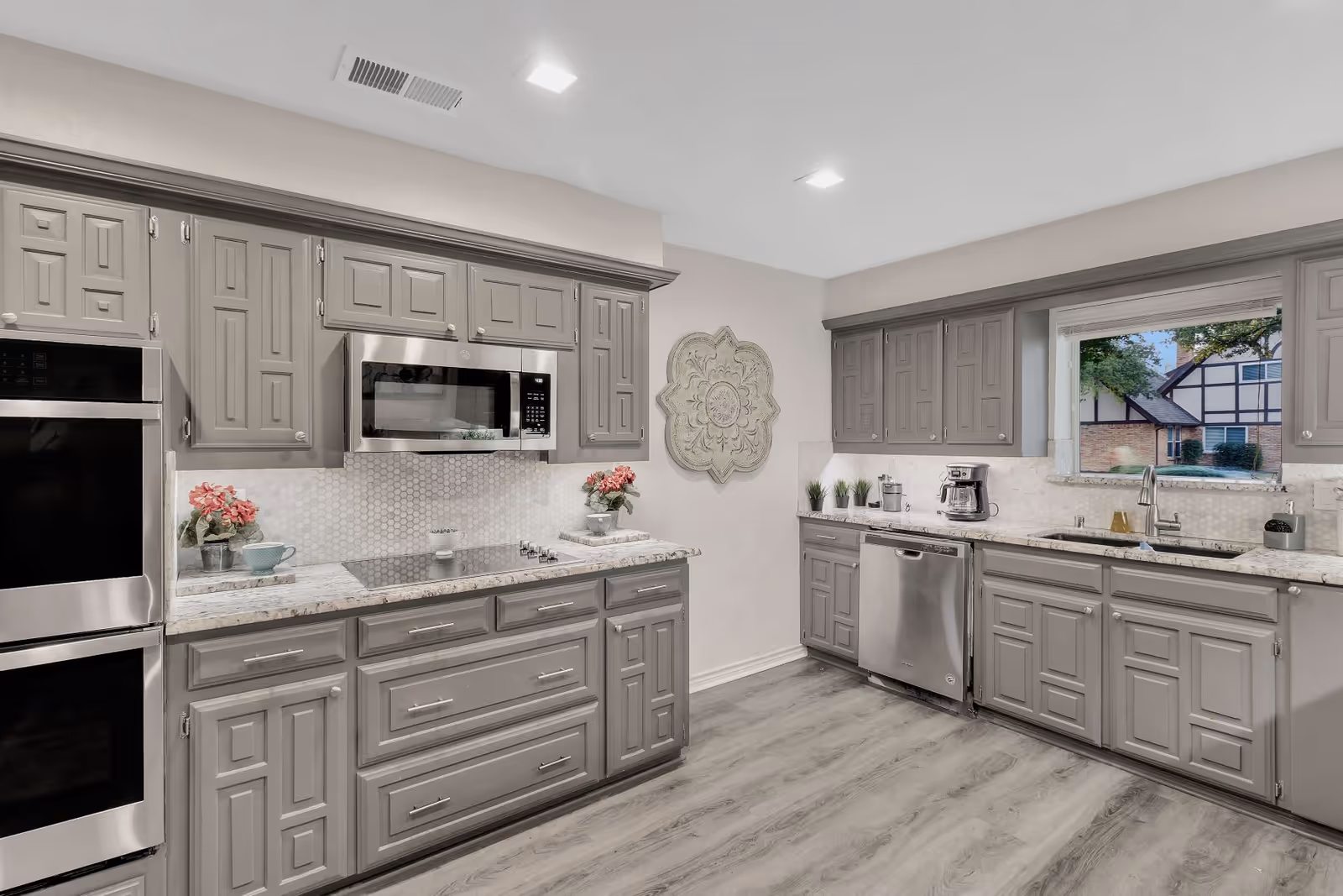Bright modern kitchen with gray cabinets, stainless steel appliances, and a window over the sink.