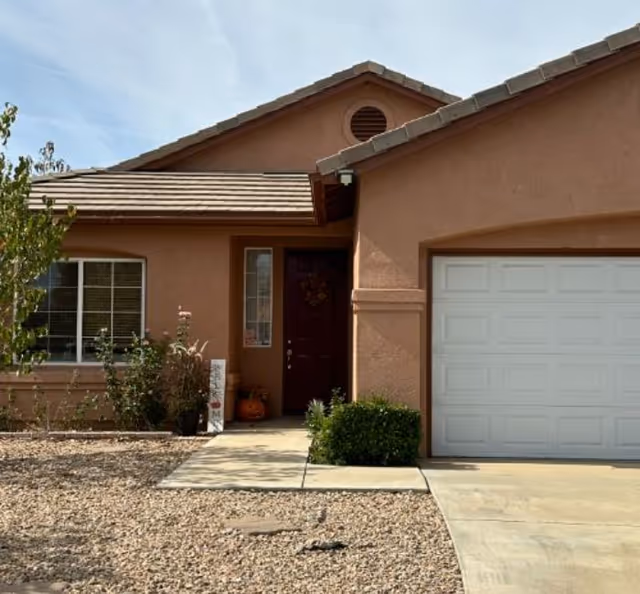 Exterior view of a peach-colored residential building with a front door and garage.