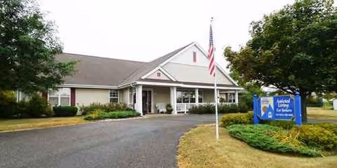 Exterior view of Our House Senior Living New Richmond Memory Care facility with flag and sign.