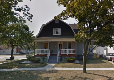Lincoln House senior living facility building with a front porch, steps, and surrounding trees.