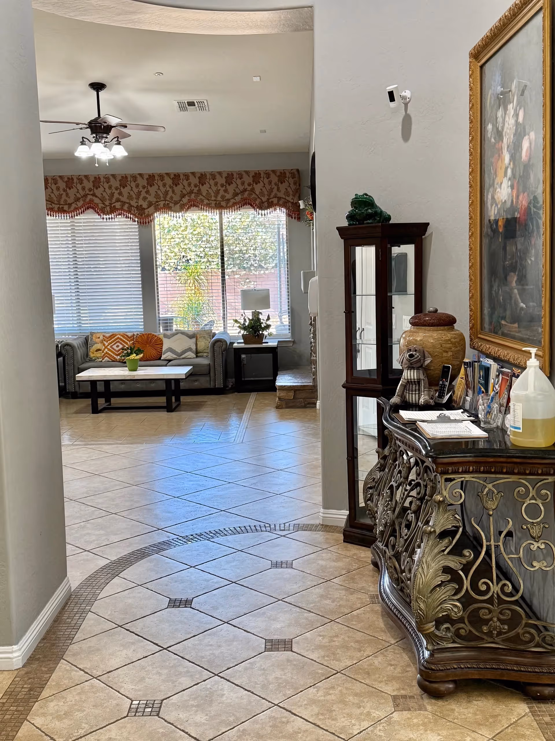 View of a sunlit living room in a senior facility with sofa and decorative cabinet.