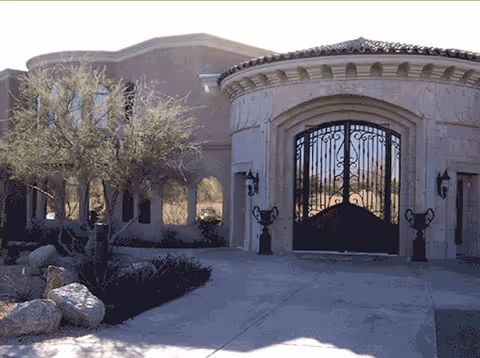 Exterior view of Heritage Cottonwood entrance with wrought iron gates and desert landscaping.