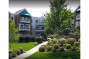 Exterior view of a multi-story senior living building with a landscaped lawn and path