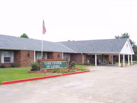 Brick care facility building with a sign, flagpole, and a covered front entrance.