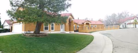 Exterior view of Sungarden Villa I with curved driveway, lawn, and beige building.