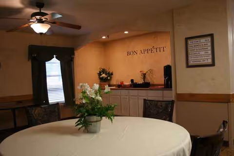 Round table with white tablecloth and potted flowers in a dining room.