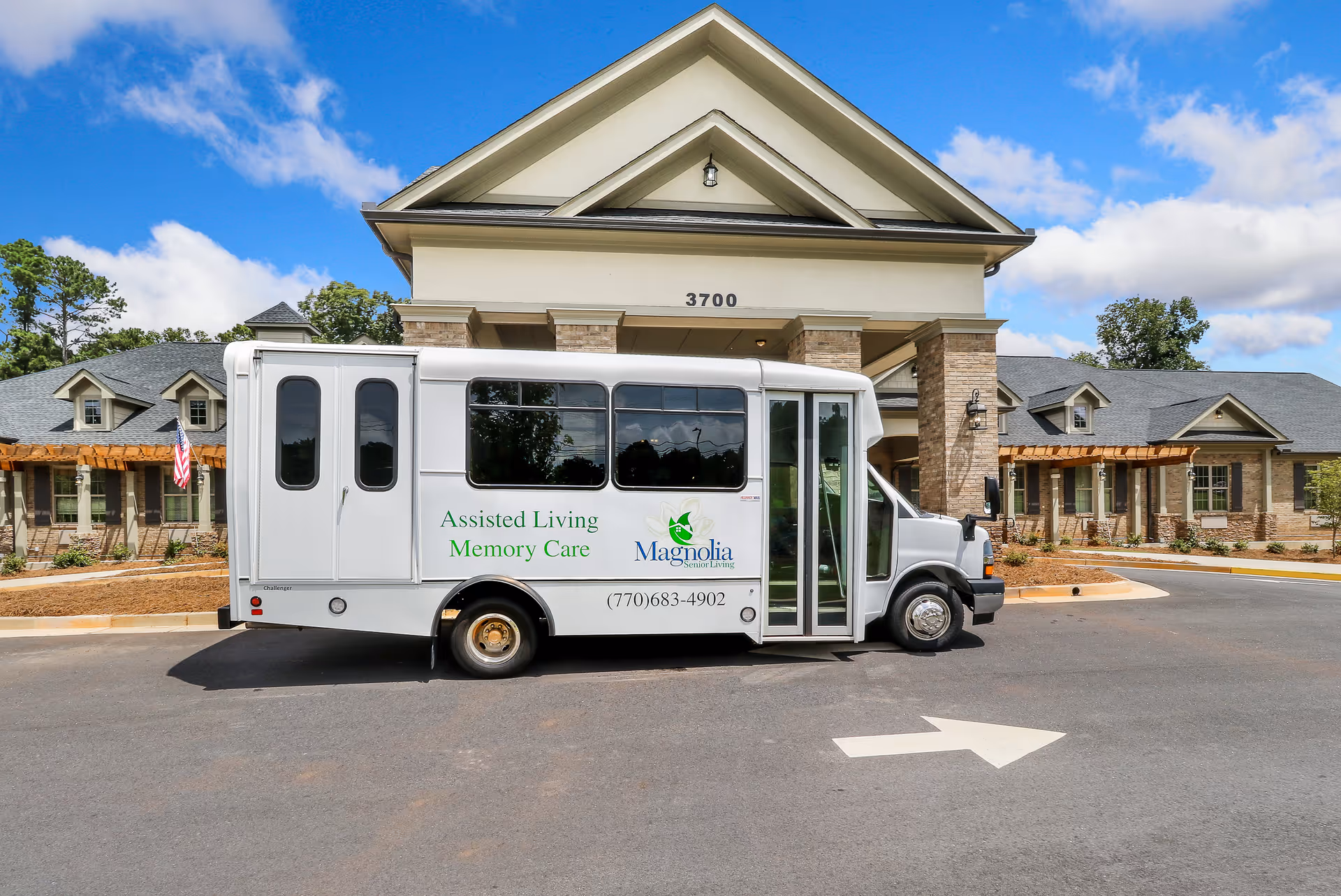 A white Magnolia Senior Living shuttle bus parked in front of the facility entrance with the building and address number 3700 visible.