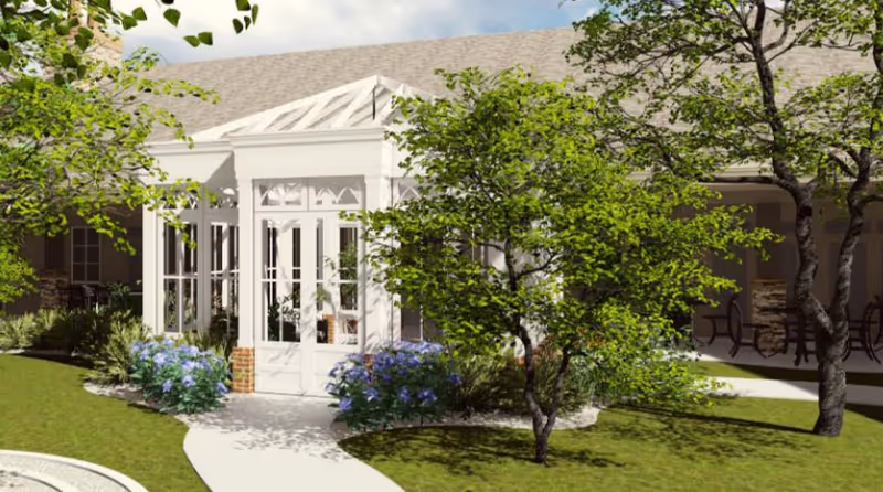 Exterior view of a white-framed sunroom entrance with glass doors surrounded by landscaping, trees, and a curved walkway.