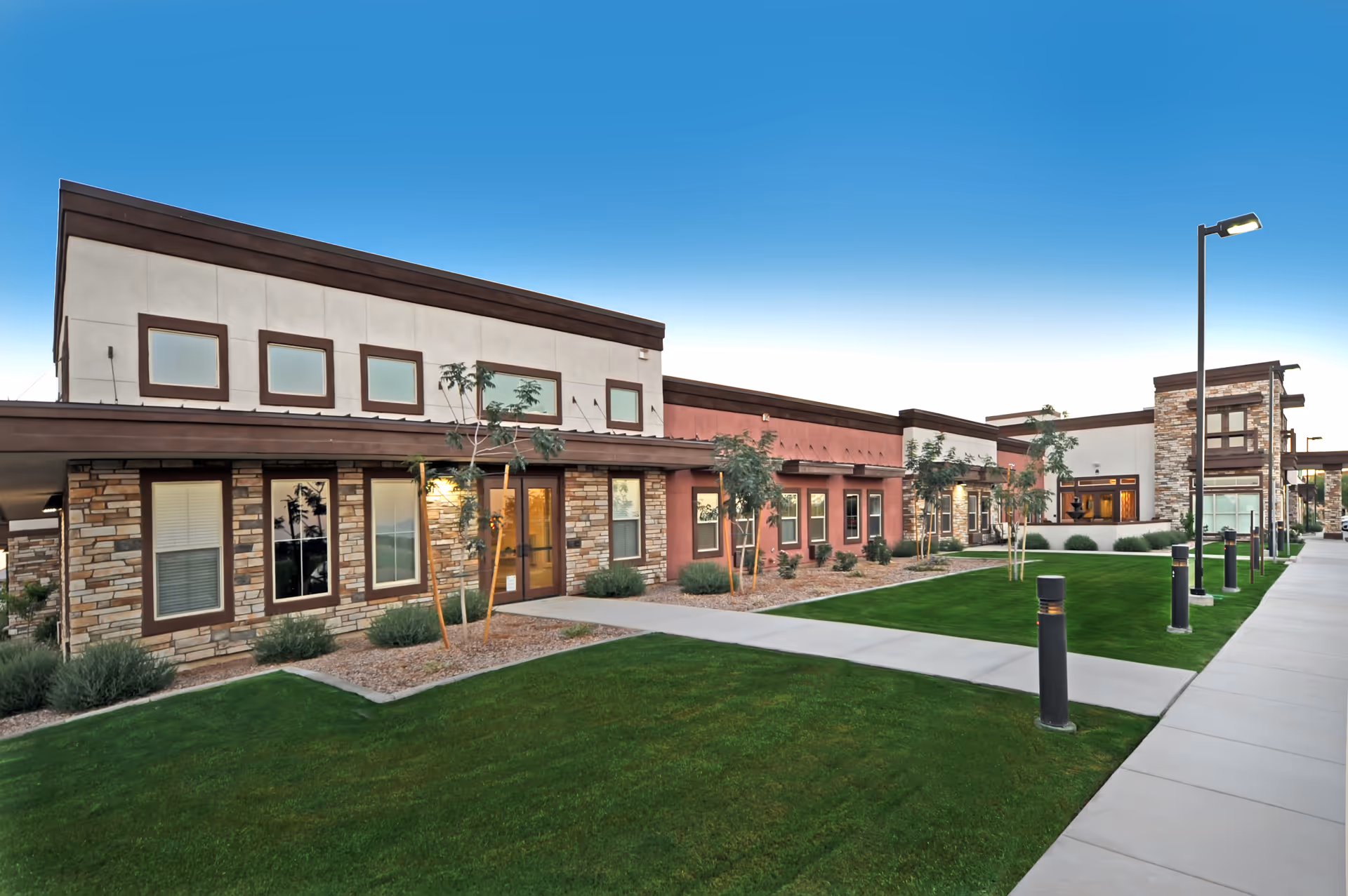 Sky Ridge senior living facility exterior with stone accents, green lawn, and walkway.