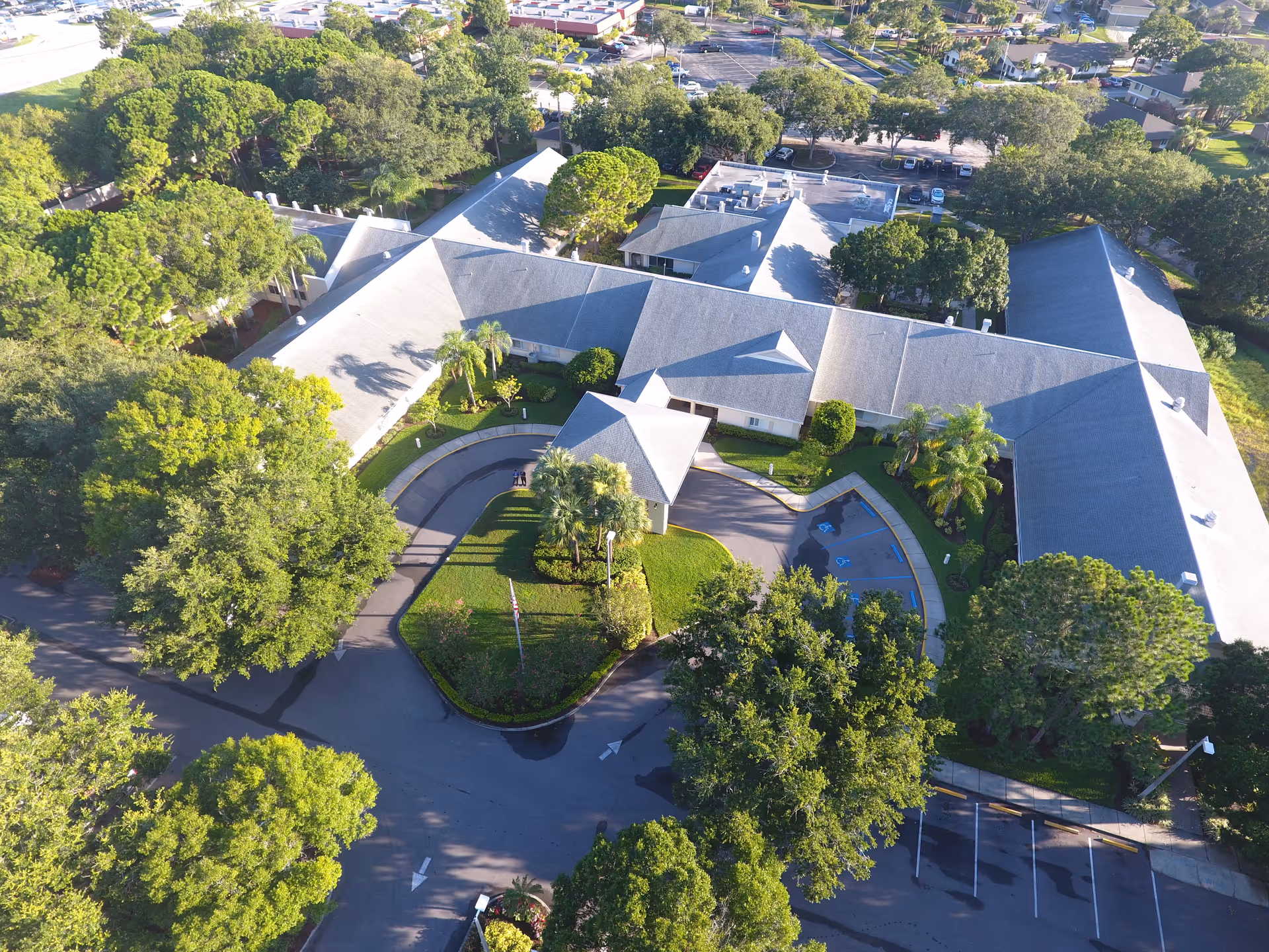 Aerial view of the Palm Garden of Pinellas building complex with a circular driveway, parking areas, and surrounding trees.