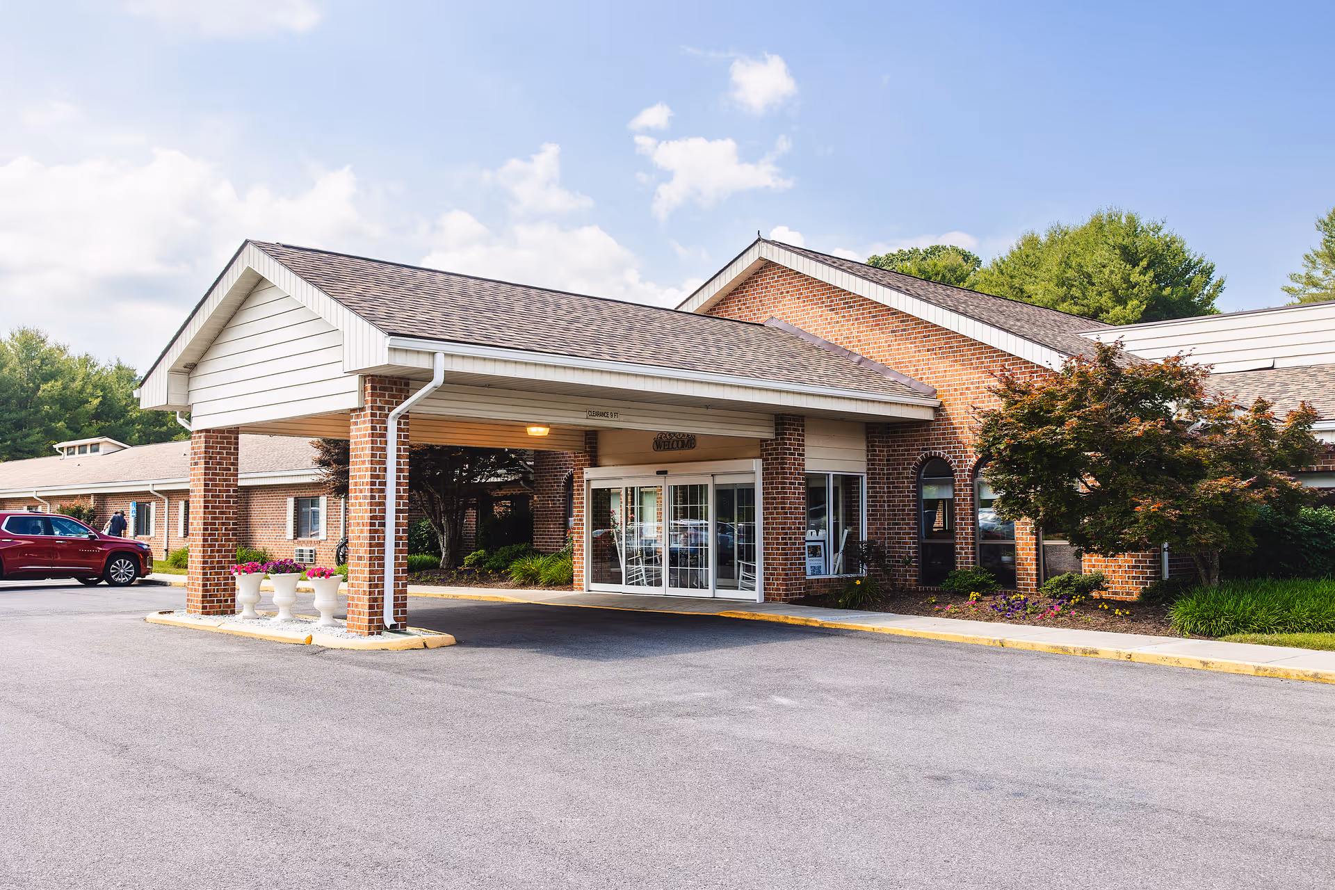 Exterior view of a brick senior living facility with a covered entrance and glass doors
