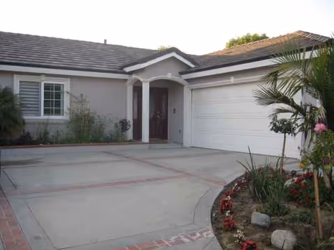 Front exterior of a single-story home with driveway, garage, and landscaped yard
