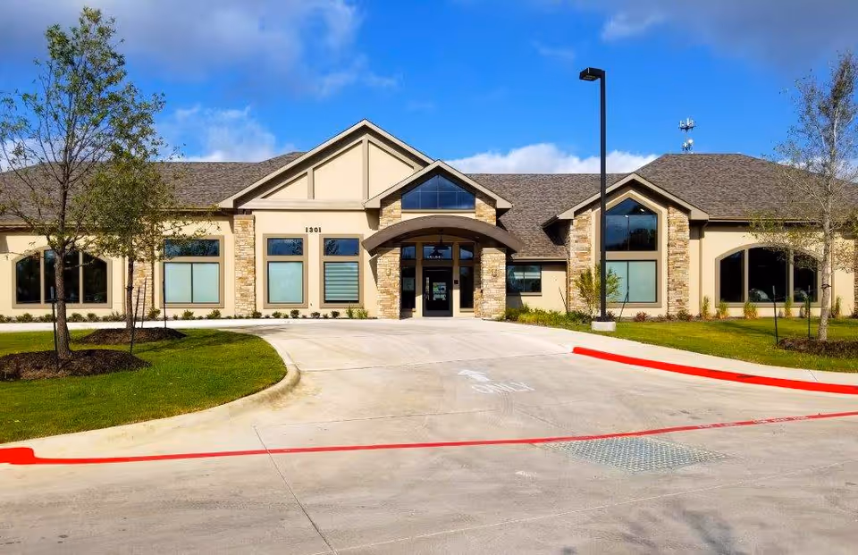 Front exterior view of Cedar Pointe Wellness And Health Center building with a driveway, manicured lawn, trees, and a clear blue sky.