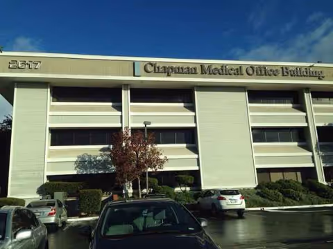 Front exterior of Chapman Medical Office Building with parked cars and landscaping