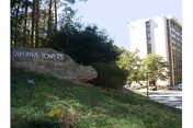 Exterior view of Smyrna Towers senior apartment building with its stone sign on a grassy slope.