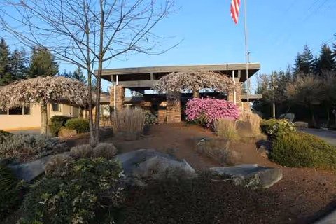 Front view of Emerald Hills Adult Family Home entrance with landscaped shrubs and flag.