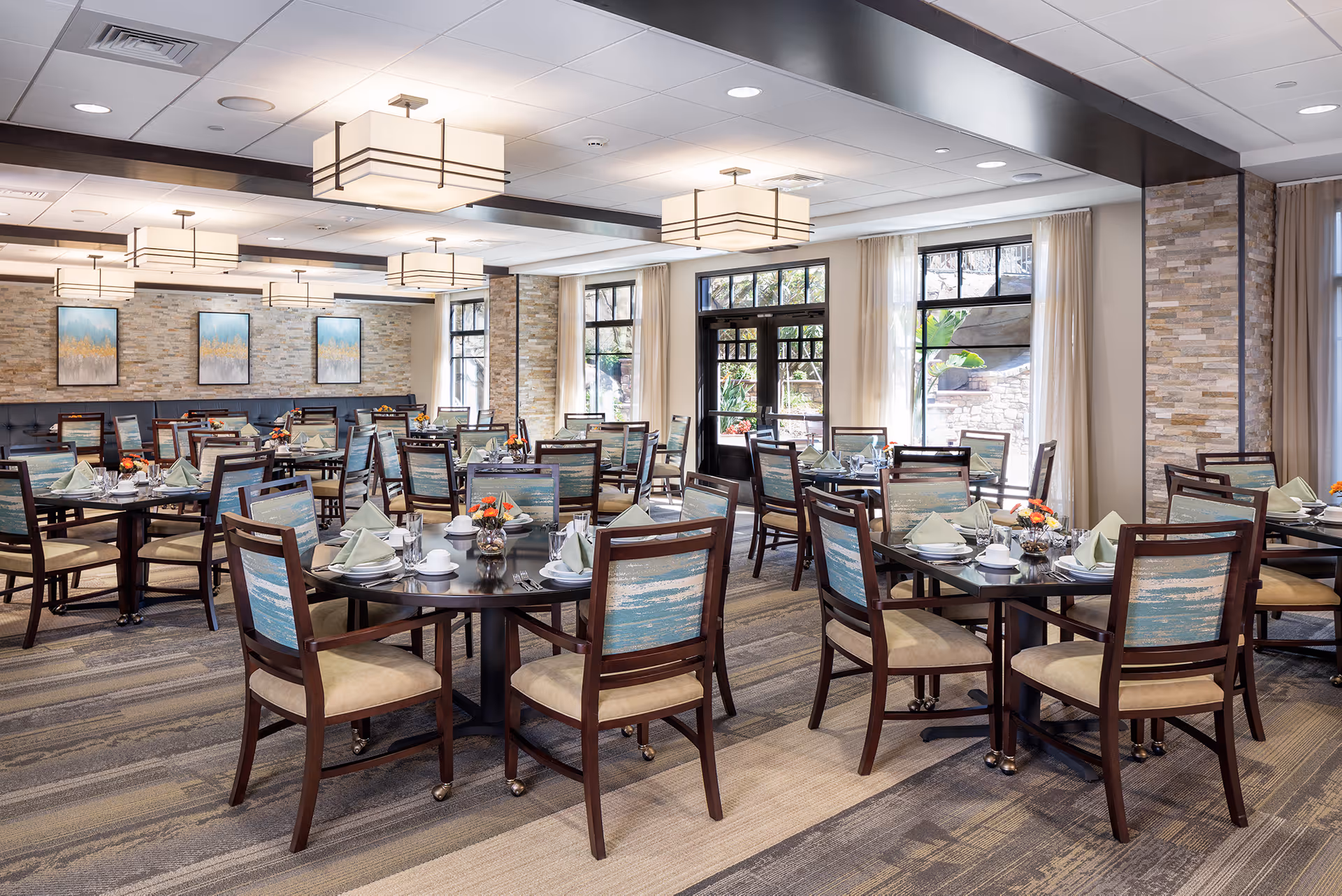 Spacious dining room with multiple set tables and chairs, large windows, and modern ceiling lights.